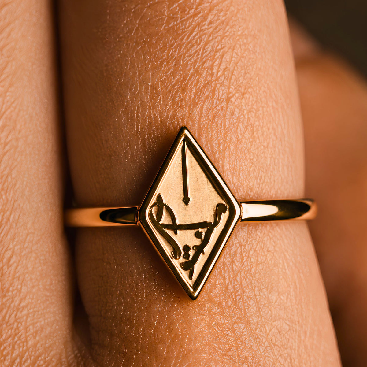 A gold plated arabic calligraphy ring featuring Maktub inspired by the meaning of destiny, shown worn on a finger.